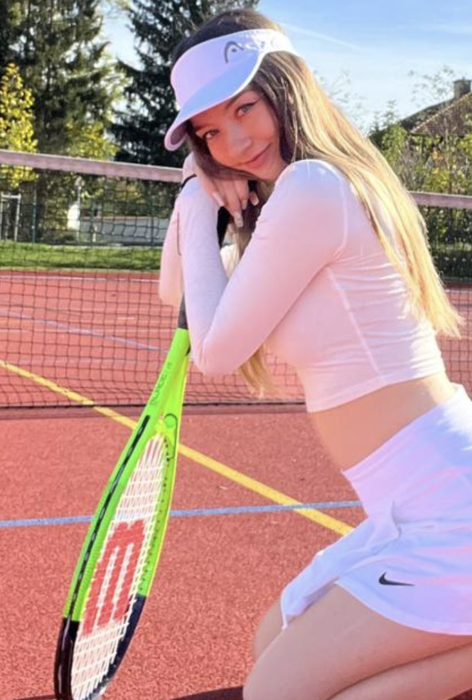 Anastasia Hill kneeling on the tennis court holding a racket