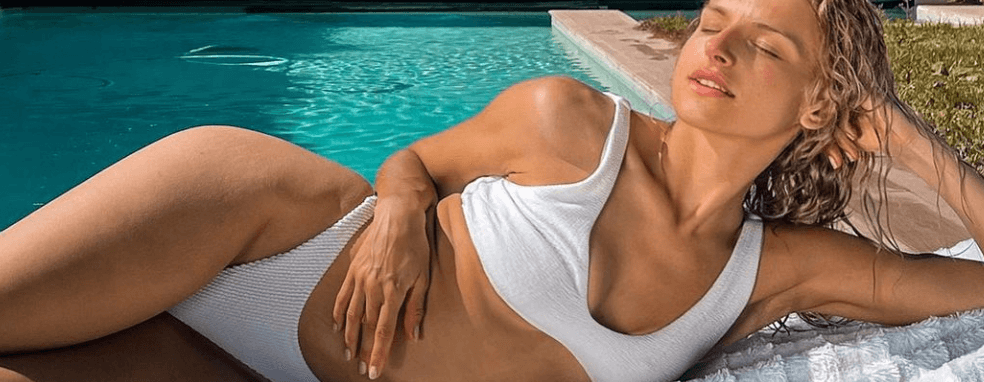 Diaga Sage con bikini blanco acostada al lado de la piscina
