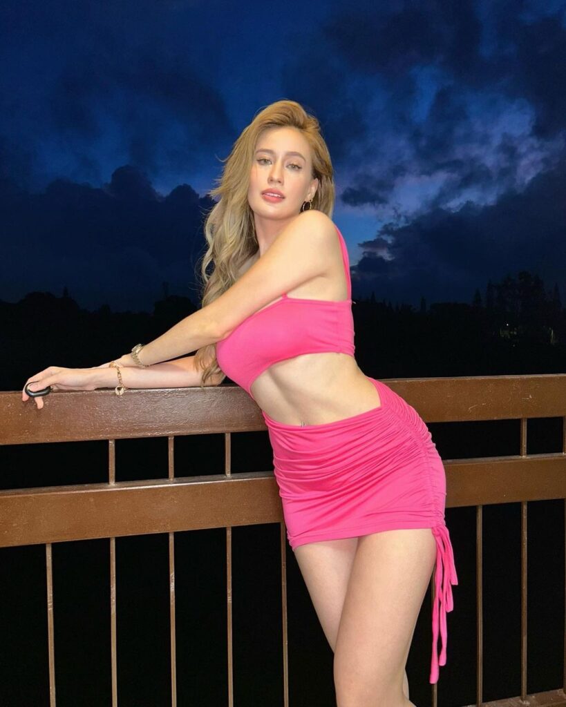 Onlyfans model  Jackie Smart wearing a pink two-piece cropped top and skirt striking an alluring pose for the camera.