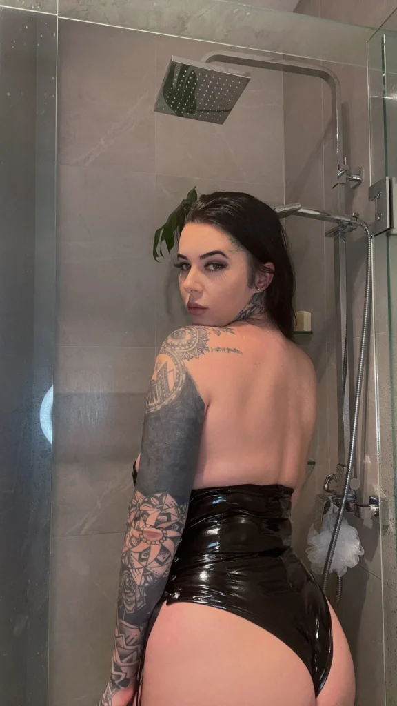 TalaMorgana (@talamorgana) Schwarzhaariges OnlyFans-Modellfoto im Badezimmer, das schwarze Latexunterwäsche trägt