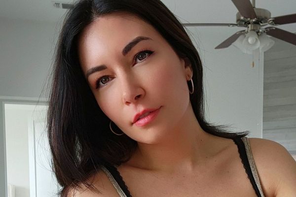 Alinity (@Alinity) une streameuse colombienne sexy portant des boucles d'oreilles à crochets et des cheveux noirs.