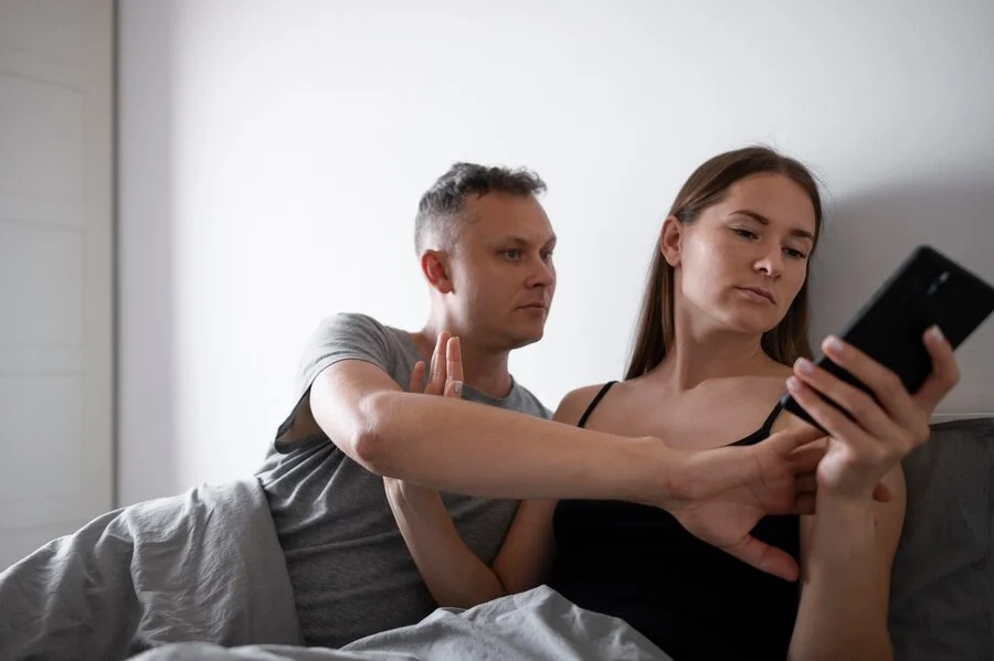 cheating onlyfans. man and woman in bed arguing in phone