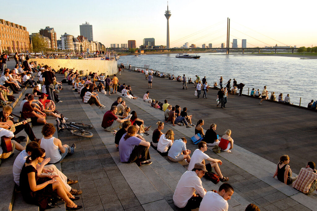 Rhine Promenade bank where hundreds of men and women are watching the sunset