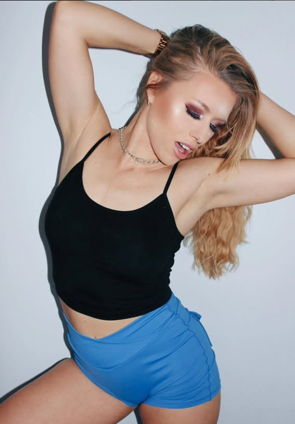 Michelle Moist dressed in a sexy black top and blue shorts.