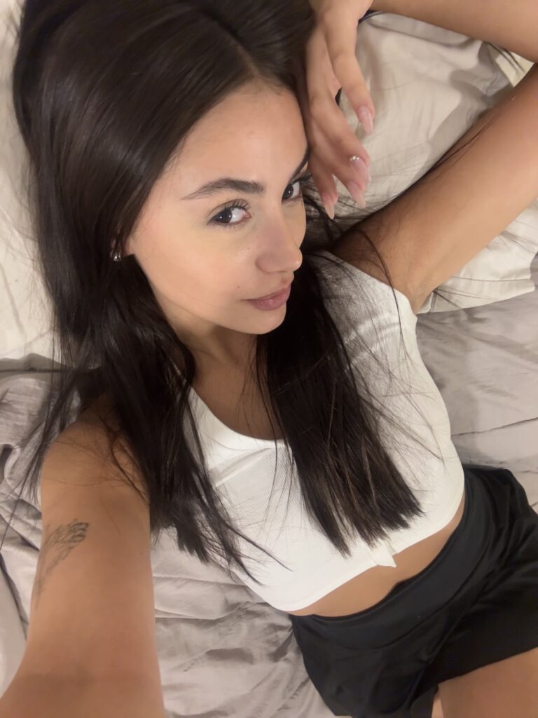 Lily Rose OnlyFans model wearing white top lying on the bed