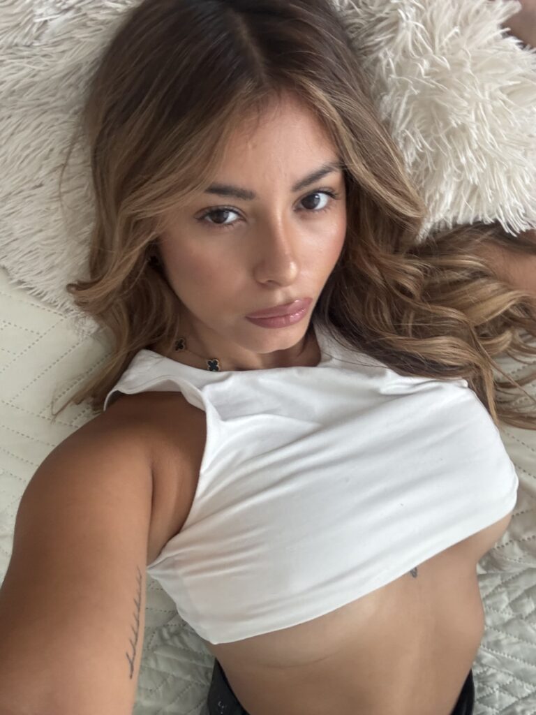 Grace Charis OnlyFans model wearing white top lying on the bed