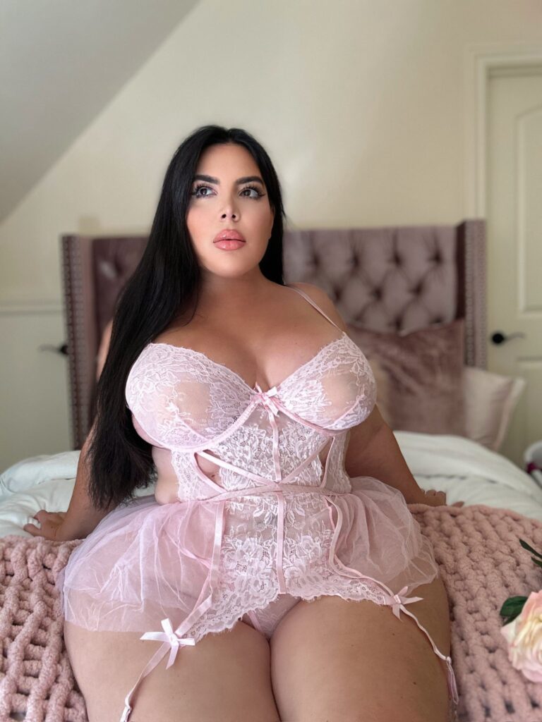Nicole Nurko OnlyFans chubby model wearing pink lingerie sitting on the bed